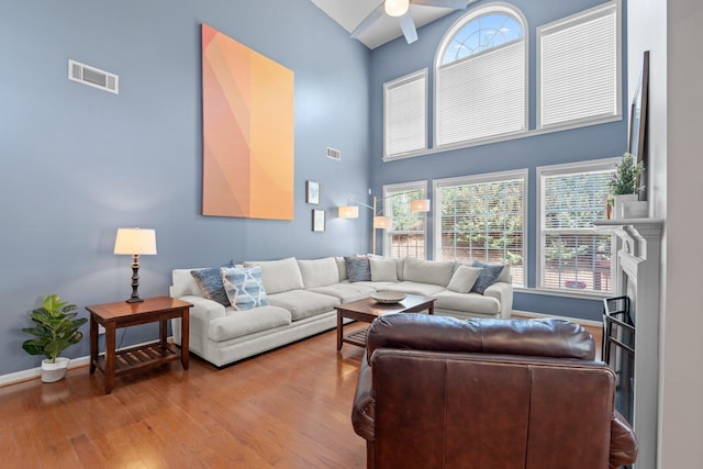 living room with ceiling fan, plenty of natural light, a high ceiling, and hardwood / wood-style flooring