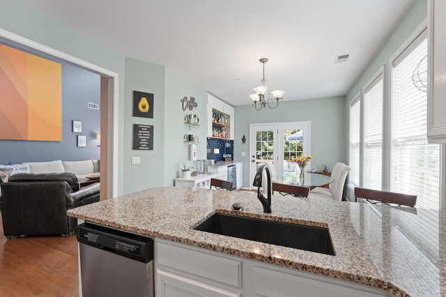 kitchen with sink, light stone counters, light hardwood / wood-style flooring, stainless steel dishwasher, and white cabinets