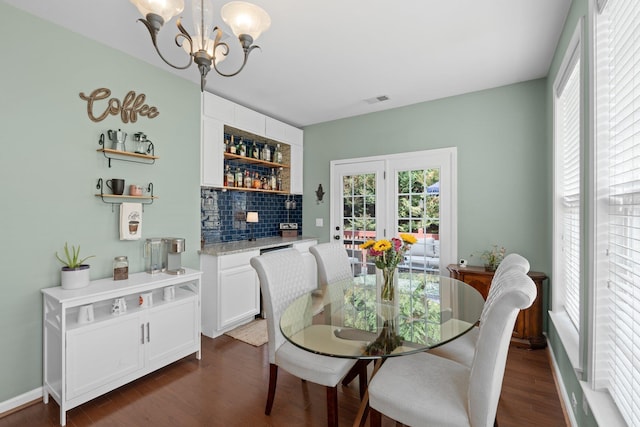 dining space featuring bar, dark hardwood / wood-style flooring, and a notable chandelier