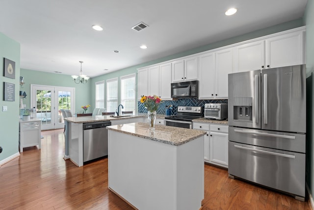 kitchen featuring appliances with stainless steel finishes, a center island, pendant lighting, and hardwood / wood-style floors