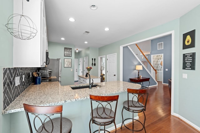 kitchen featuring kitchen peninsula, a kitchen bar, dark hardwood / wood-style floors, and sink