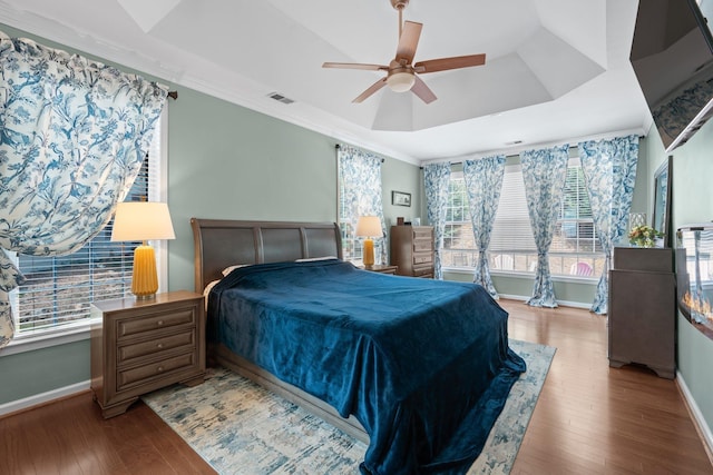 bedroom with a raised ceiling, ceiling fan, wood-type flooring, and ornamental molding