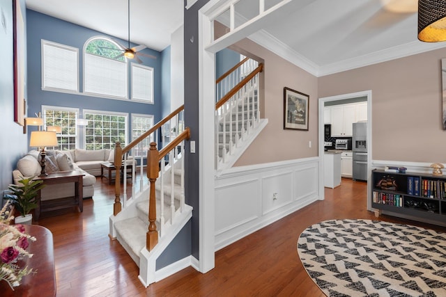 staircase featuring hardwood / wood-style floors, a towering ceiling, ceiling fan, and crown molding