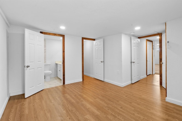 unfurnished bedroom with ensuite bathroom and light hardwood / wood-style floors