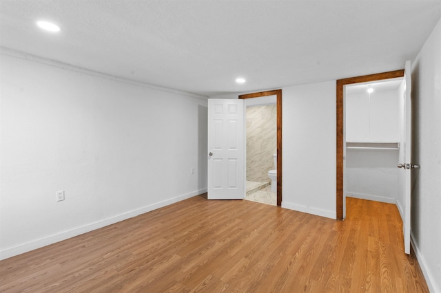 unfurnished bedroom with light wood-type flooring and connected bathroom