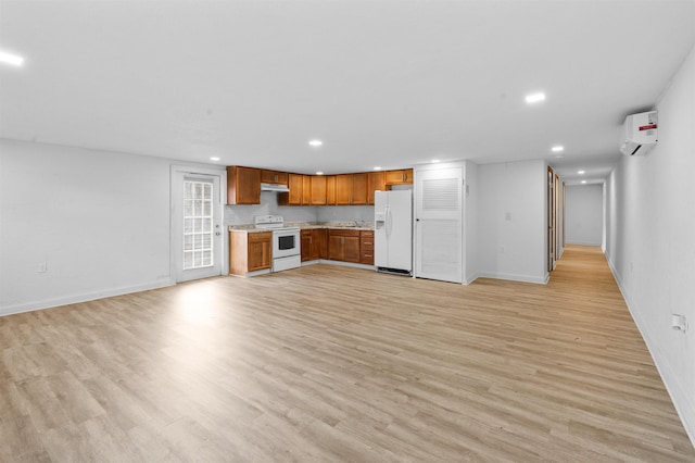 kitchen with a wall mounted air conditioner, light hardwood / wood-style floors, and white appliances