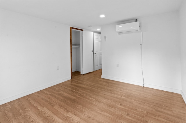 spare room with a wall mounted air conditioner and light hardwood / wood-style flooring