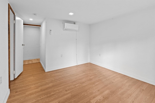 empty room with a wall mounted air conditioner and light wood-type flooring