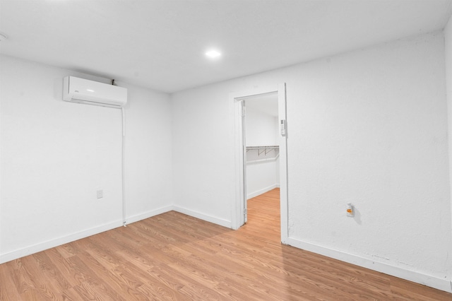 empty room featuring an AC wall unit and light hardwood / wood-style floors