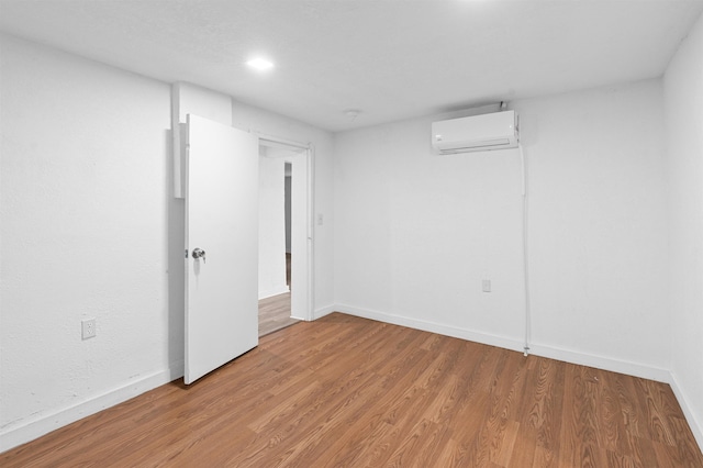 empty room with a wall mounted air conditioner and hardwood / wood-style floors