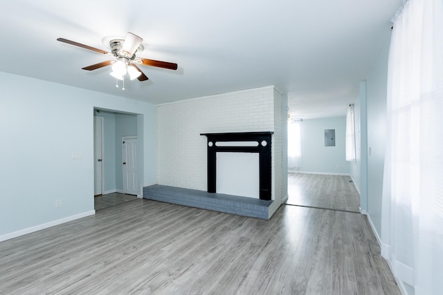 unfurnished living room with a brick fireplace, light hardwood / wood-style floors, electric panel, and ceiling fan