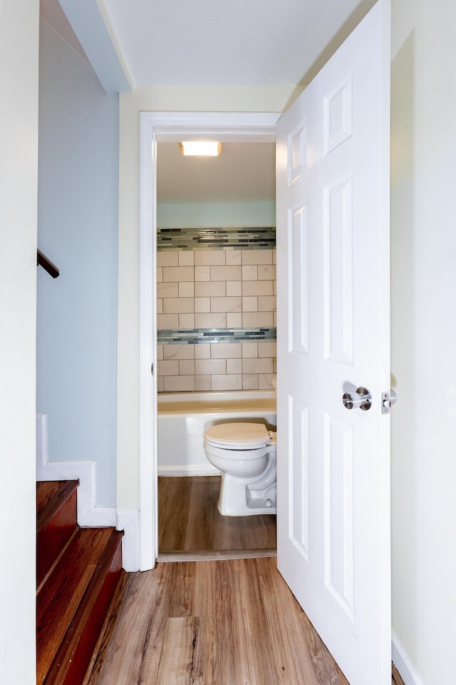 bathroom featuring hardwood / wood-style floors, toilet, and a tub to relax in