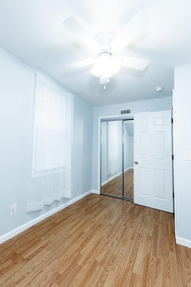 unfurnished bedroom with ceiling fan, light wood-type flooring, and a closet