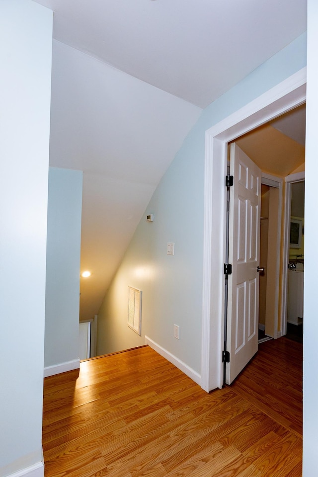 hallway featuring lofted ceiling and light hardwood / wood-style flooring