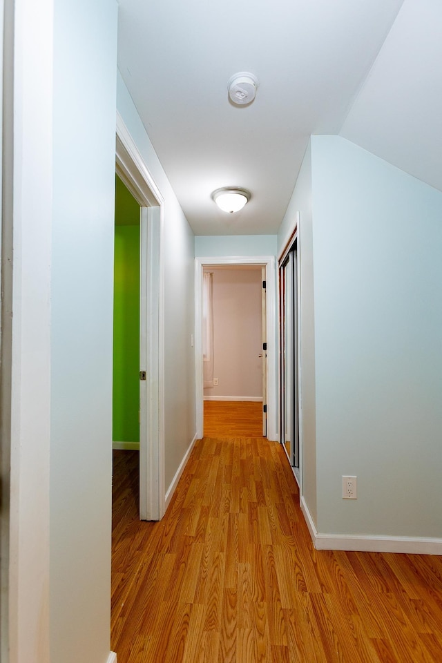 hall with vaulted ceiling and light hardwood / wood-style floors