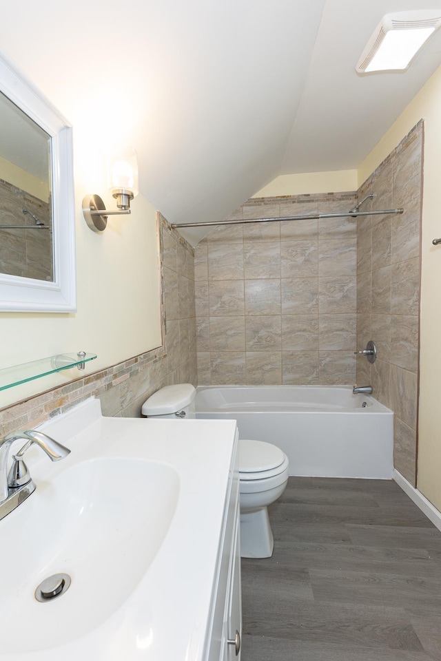 full bathroom featuring wood-type flooring, tile walls, tiled shower / bath combo, vanity, and toilet