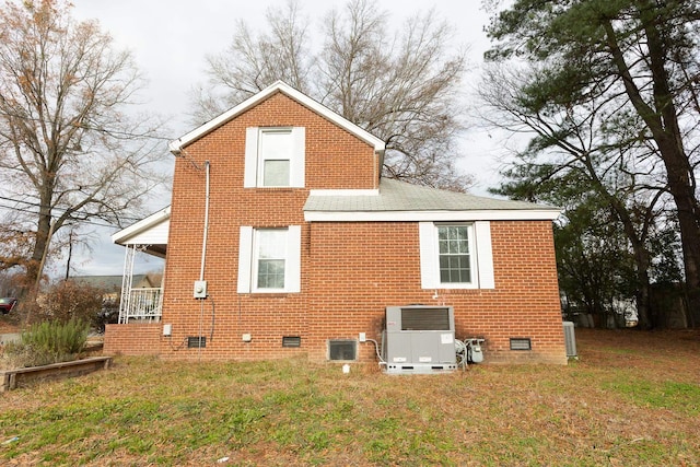 rear view of house featuring cooling unit and a lawn