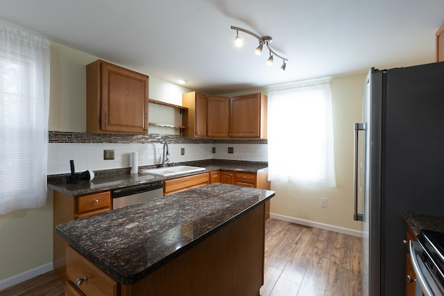 kitchen with tasteful backsplash, stainless steel appliances, sink, and hardwood / wood-style flooring