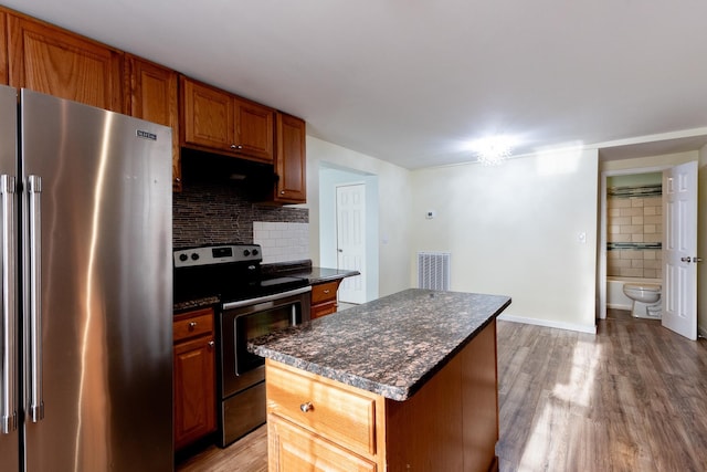 kitchen with extractor fan, a kitchen island, backsplash, stainless steel appliances, and light hardwood / wood-style flooring