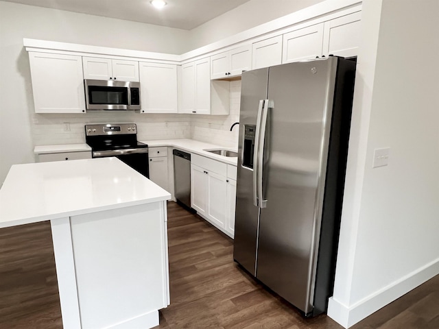 kitchen with dark hardwood / wood-style flooring, stainless steel appliances, sink, white cabinetry, and a kitchen island