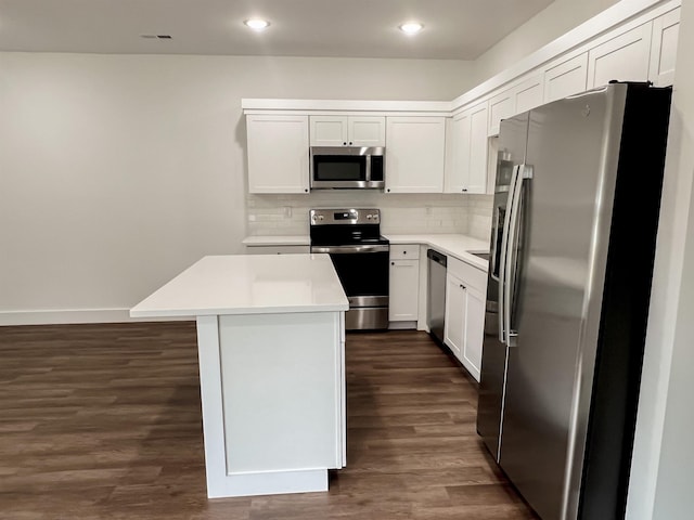 kitchen with a center island, white cabinets, decorative backsplash, dark hardwood / wood-style floors, and appliances with stainless steel finishes