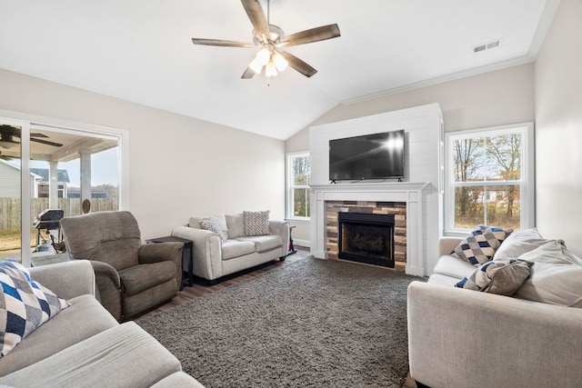 living room with a stone fireplace, ceiling fan, crown molding, and lofted ceiling