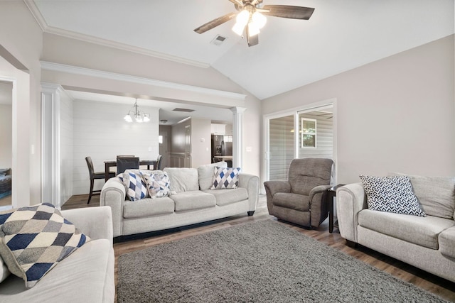 living room featuring ceiling fan with notable chandelier, vaulted ceiling, ornate columns, ornamental molding, and dark hardwood / wood-style flooring