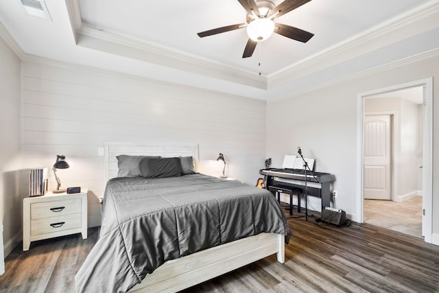 bedroom with a raised ceiling, ceiling fan, crown molding, and dark wood-type flooring