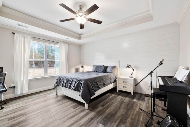 bedroom featuring hardwood / wood-style flooring, ceiling fan, ornamental molding, and a tray ceiling