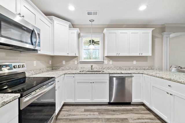 kitchen featuring sink, stainless steel appliances, pendant lighting, white cabinets, and ornamental molding