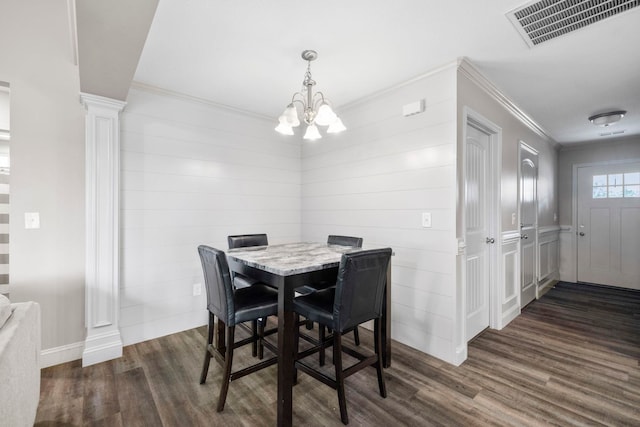 dining area featuring dark hardwood / wood-style floors, ornate columns, crown molding, and a chandelier