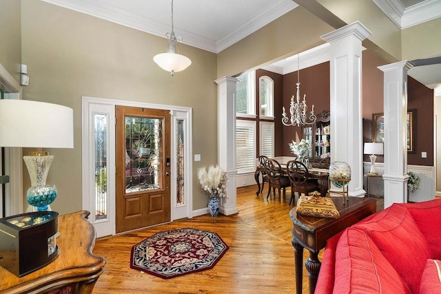 foyer entrance with a chandelier, ornamental molding, ornate columns, and a healthy amount of sunlight