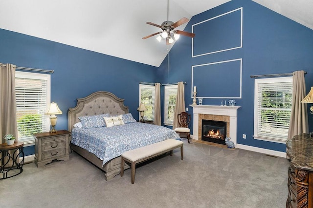 carpeted bedroom featuring multiple windows, ceiling fan, high vaulted ceiling, and a tiled fireplace