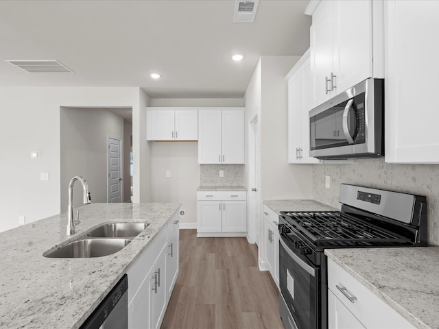 kitchen with white cabinetry, sink, light stone countertops, and appliances with stainless steel finishes