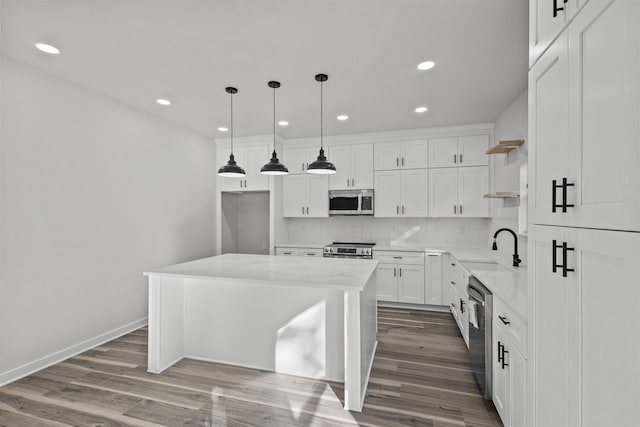 kitchen featuring light stone countertops, stainless steel appliances, white cabinets, a center island, and hanging light fixtures