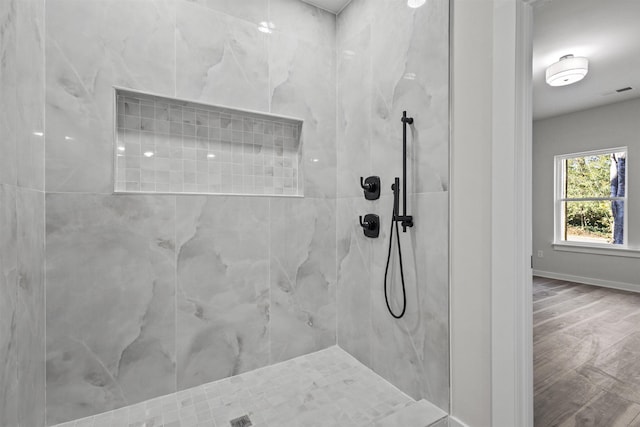 bathroom featuring a tile shower and wood-type flooring