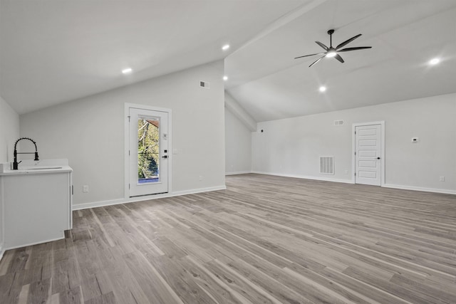 unfurnished living room featuring high vaulted ceiling, light hardwood / wood-style flooring, ceiling fan, and sink