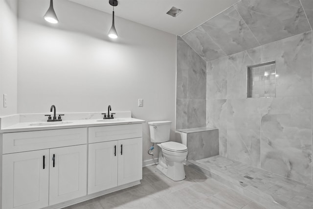 bathroom featuring tiled shower, vanity, and toilet