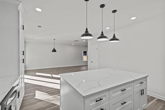 kitchen featuring light stone counters, wood-type flooring, decorative light fixtures, white cabinets, and a center island