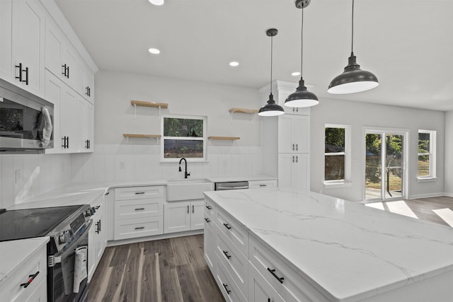 kitchen with appliances with stainless steel finishes, dark wood-type flooring, sink, white cabinetry, and hanging light fixtures