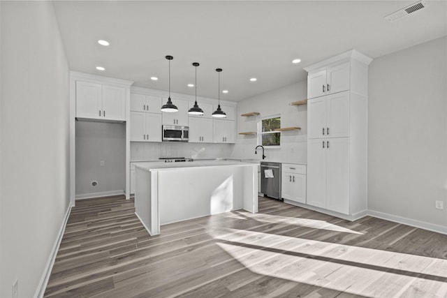 kitchen with white cabinets, light wood-type flooring, stainless steel appliances, and a kitchen island