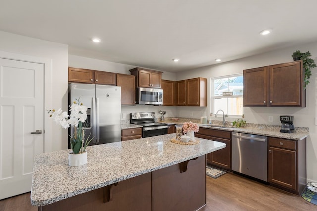 kitchen featuring appliances with stainless steel finishes, a kitchen breakfast bar, sink, a center island, and light hardwood / wood-style floors