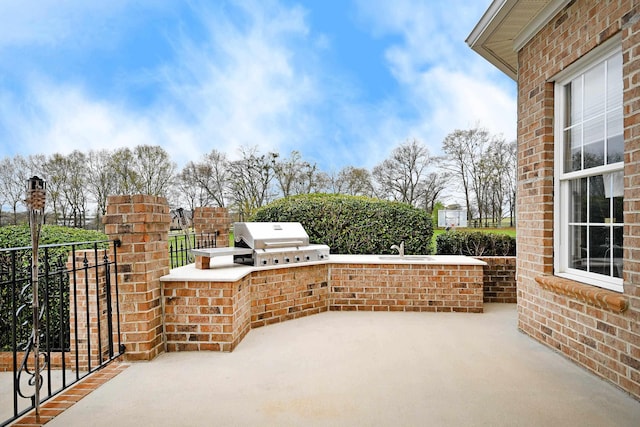 view of patio featuring an outdoor kitchen, area for grilling, and sink