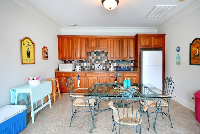 kitchen featuring decorative backsplash, crown molding, and white appliances