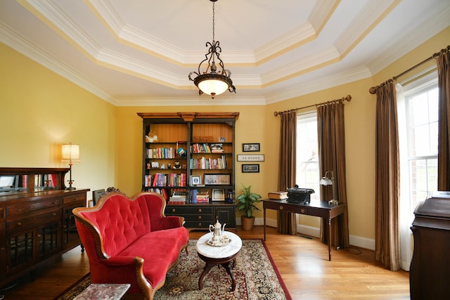 living area featuring a tray ceiling, light hardwood / wood-style flooring, and crown molding