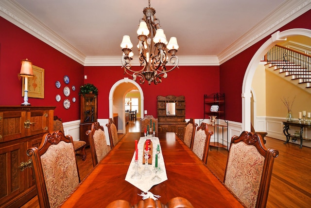 dining space with hardwood / wood-style flooring, ornamental molding, and a notable chandelier