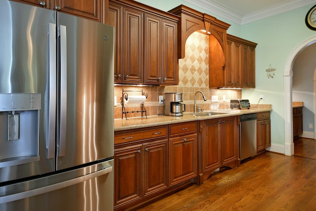 kitchen featuring sink, crown molding, dark hardwood / wood-style floors, light stone countertops, and stainless steel appliances