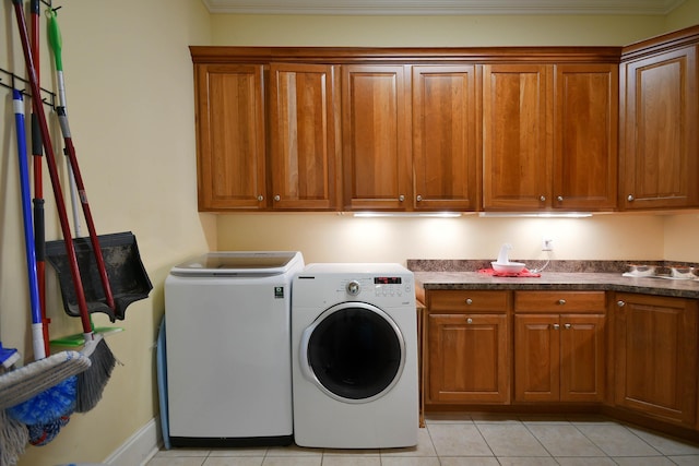 clothes washing area with separate washer and dryer, light tile patterned floors, and cabinets