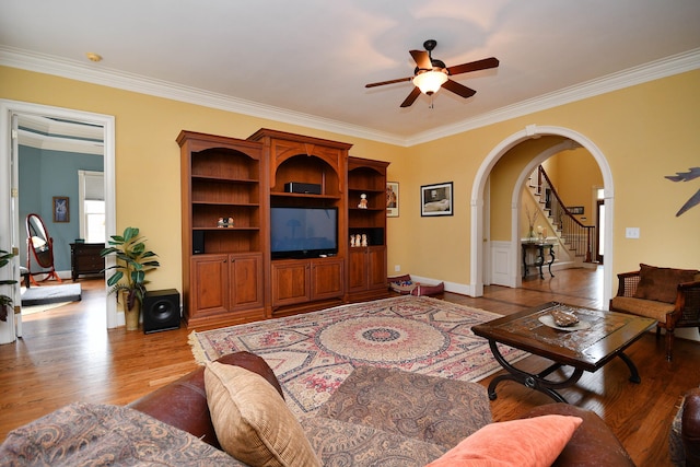 living room featuring ceiling fan, ornamental molding, and light wood-type flooring