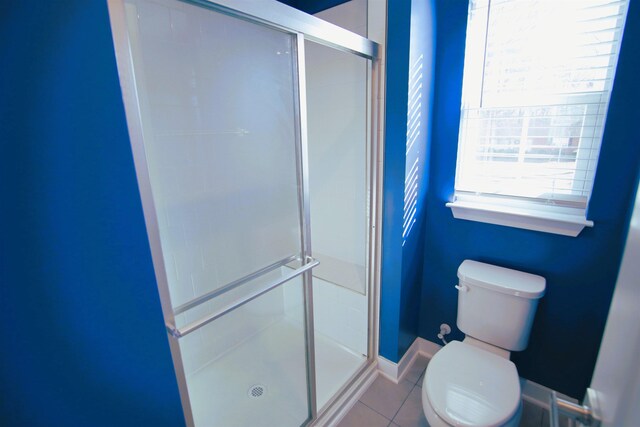 bathroom featuring tile patterned floors, toilet, and walk in shower